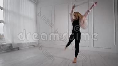 年轻漂亮的金发女郎正在白色的舞厅里排练她的<strong>舞蹈表演</strong>，跳着，旋转着